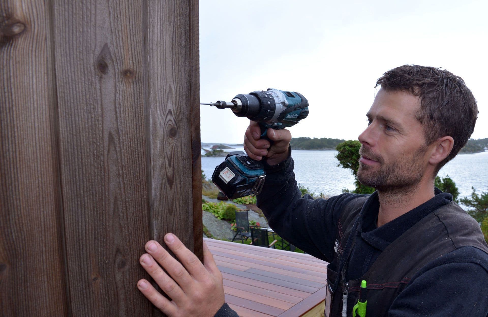 Mann som skrur fast kledning med fasadeskruer.