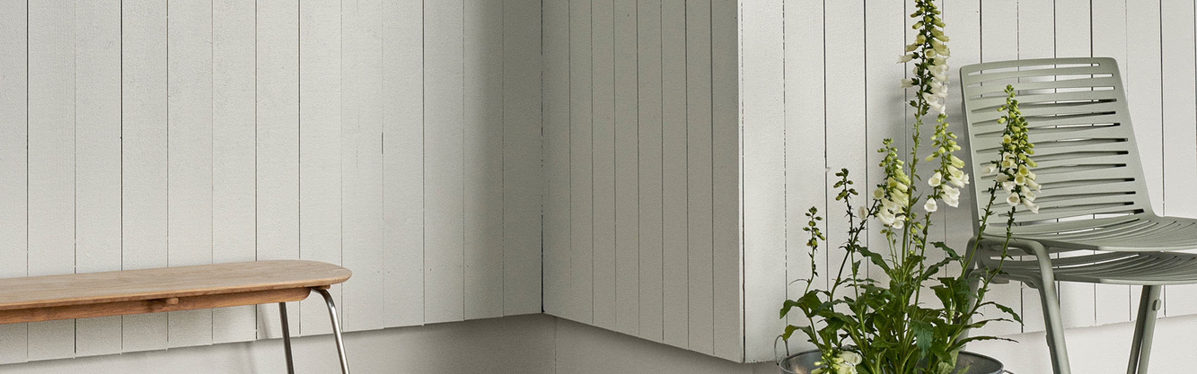 Lys maling og beis på husvegg med hagemøbler foran