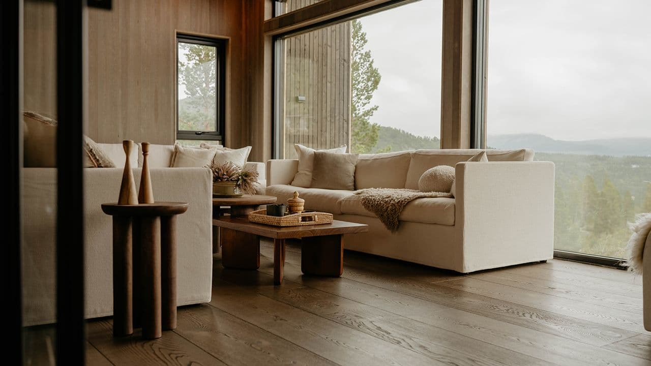 Gulv i mørk eik i moderne stue med store vinduer.