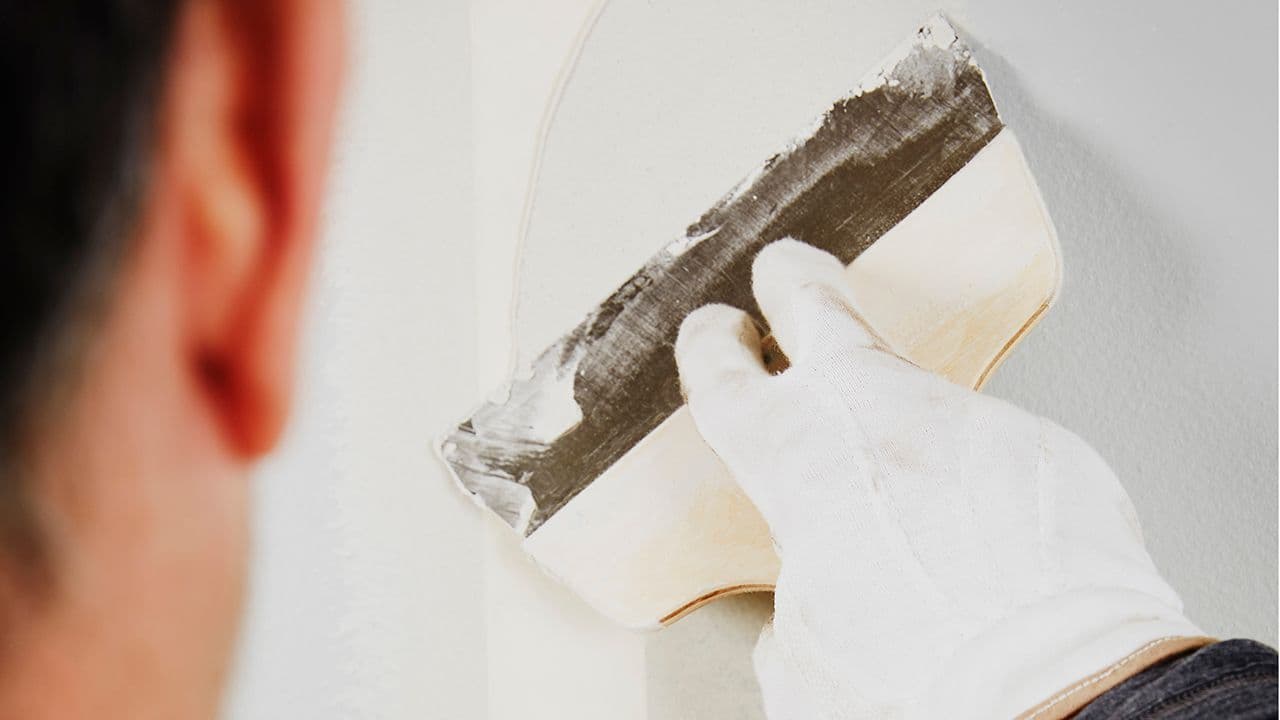 Nærbilde av mann som sparkler vegg før han skal male inne.