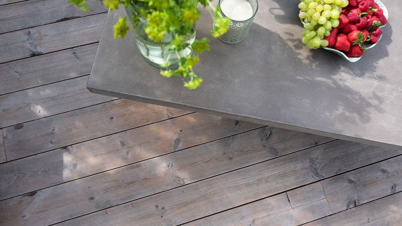 Termofuru terrassebord på terrasse med steinbord med fruktfat og pyntegjenstander.