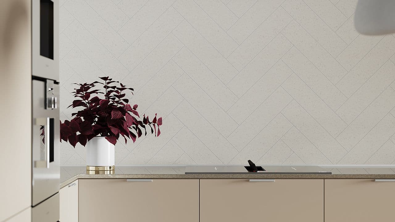 Veggplate over kjøkkenbenken i fiskebeinsmønster på nytt kjøkken med beige kjøkkeninnredning.