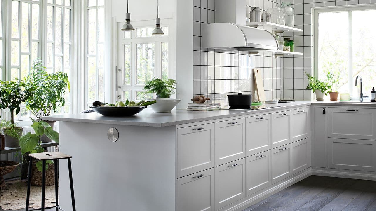 Hvitt kjøkken med lys benkeplater og hvite fliser på veggene.