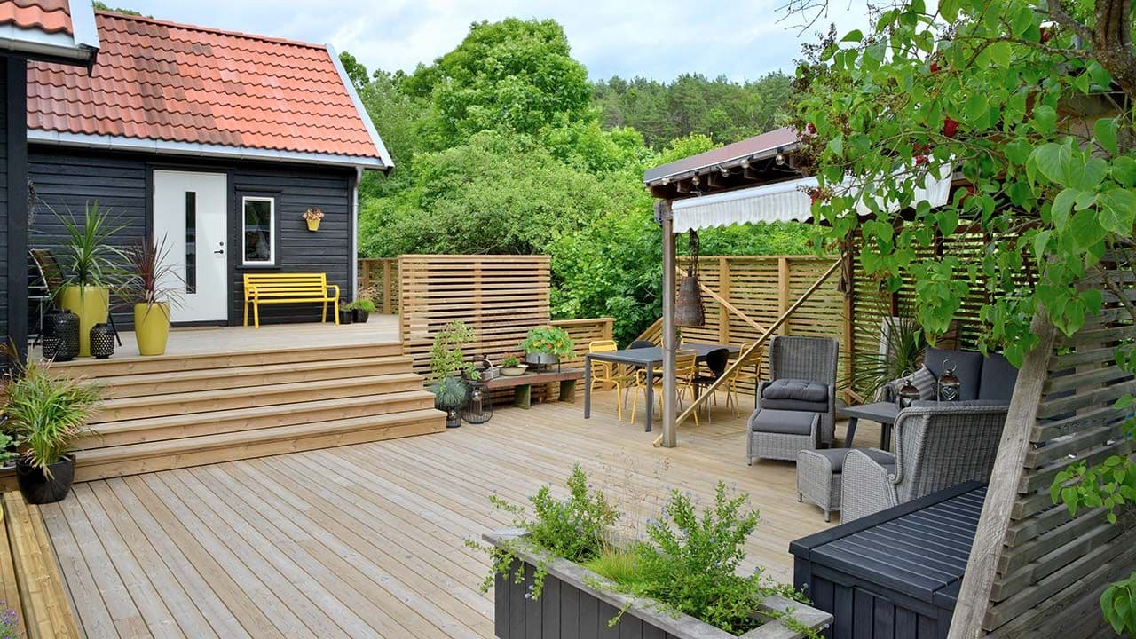 Stor terrasse med terrassebord i trykkimpregnert furu (CU-impregnert), pergola, levegg og trapp.