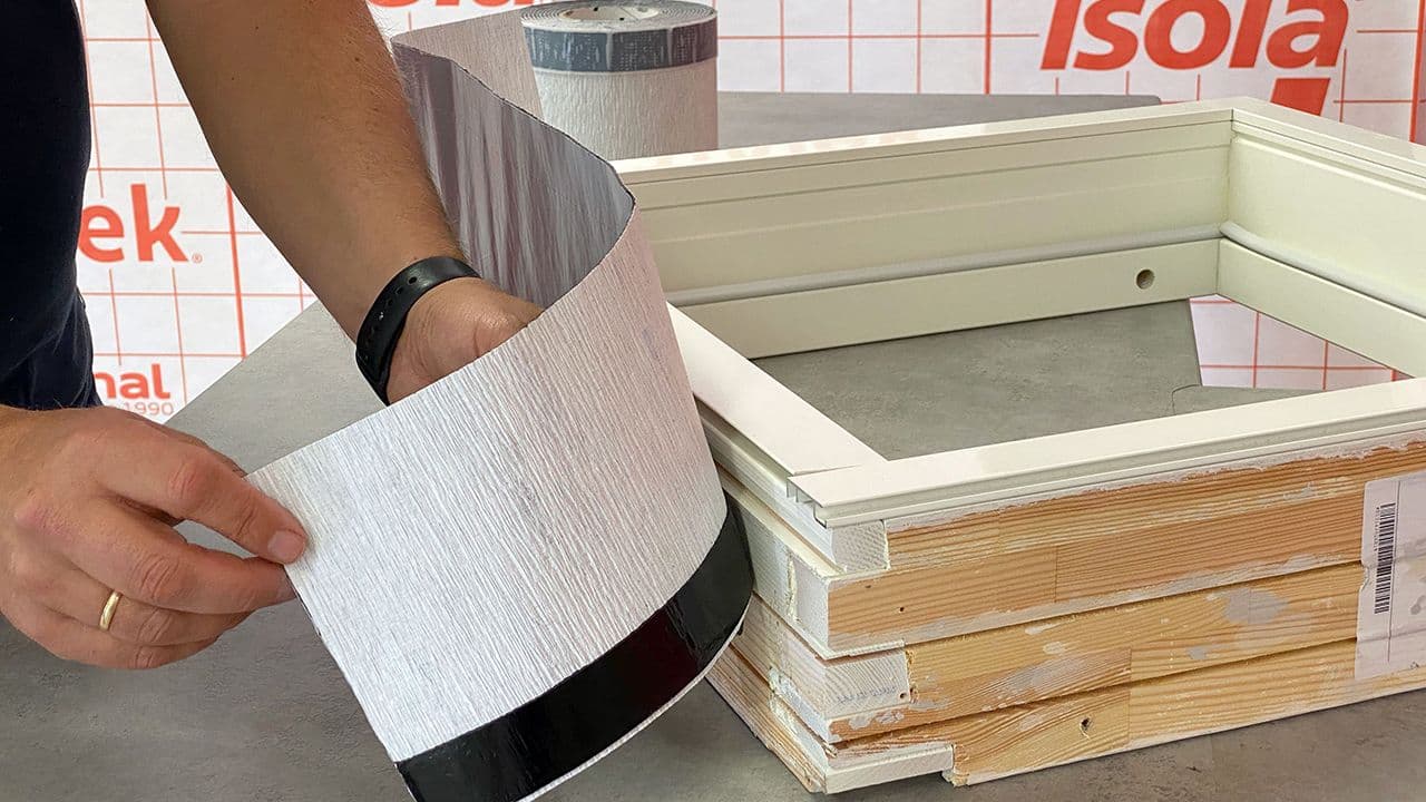 Mann somdemonstrerer hvordan man legger vindtetting rundt vindu.