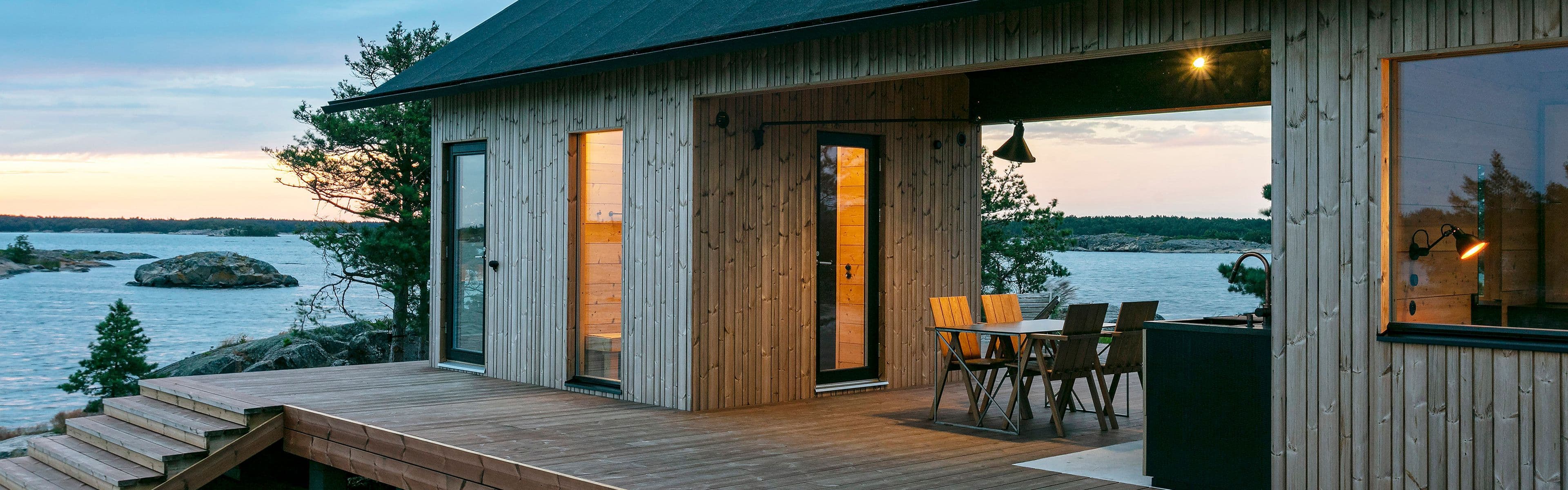 Hytte ved sjøen med kledning av varmebehandlet furu.