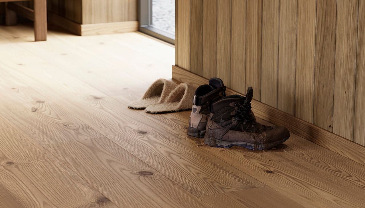 Gang med våte sko på mørkt furugulv i høytrykkslaminat.