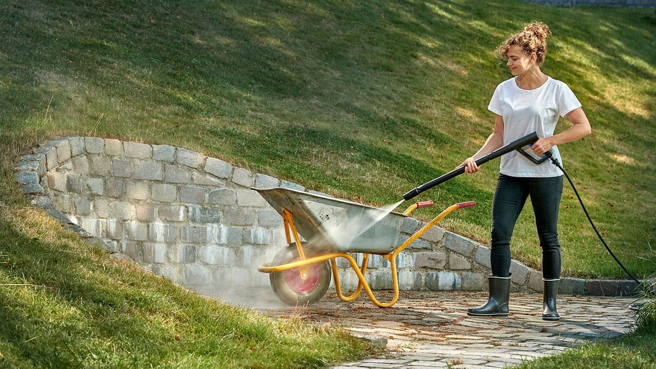 Kvinne som spyler uteplass med høytrykkspyler.