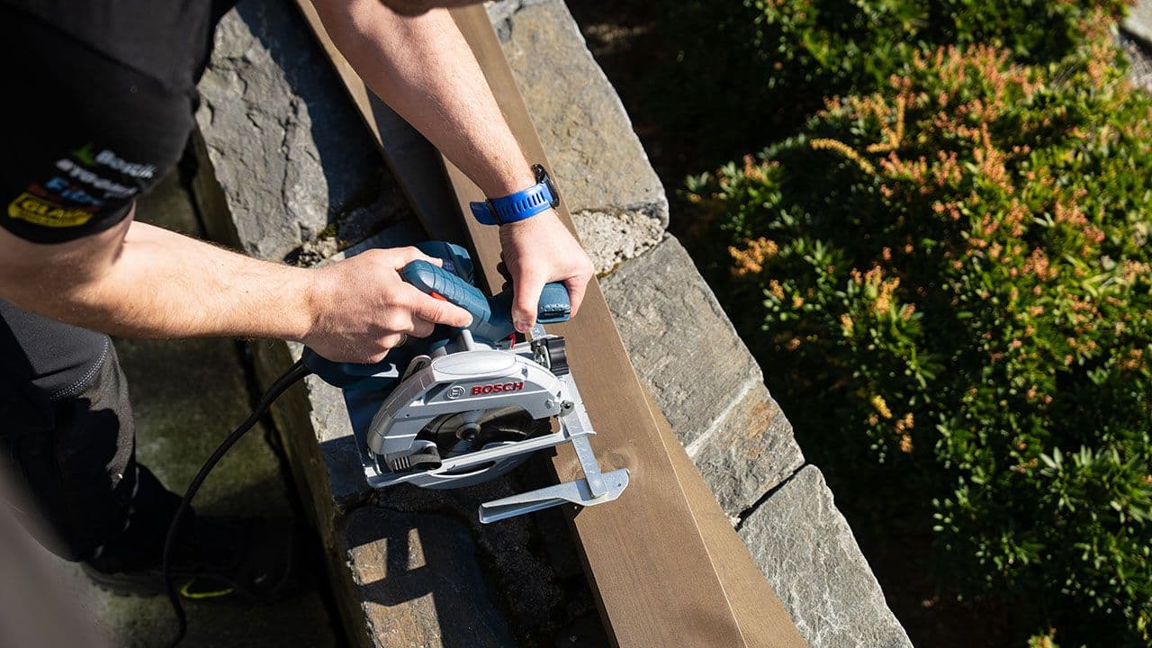 Person som bruker sirkelsag på terrassebord.