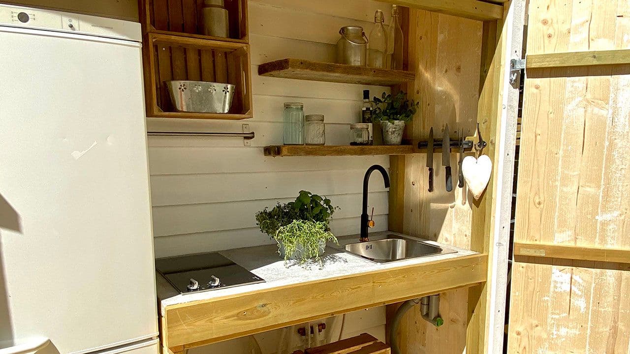 Utekjøkken på terrasse med åpne hyller som kan lukkes vekk med dør.