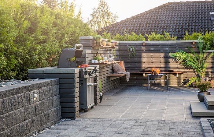 Hageheller på stor uteplass med hagemur som danner blomsterbed.