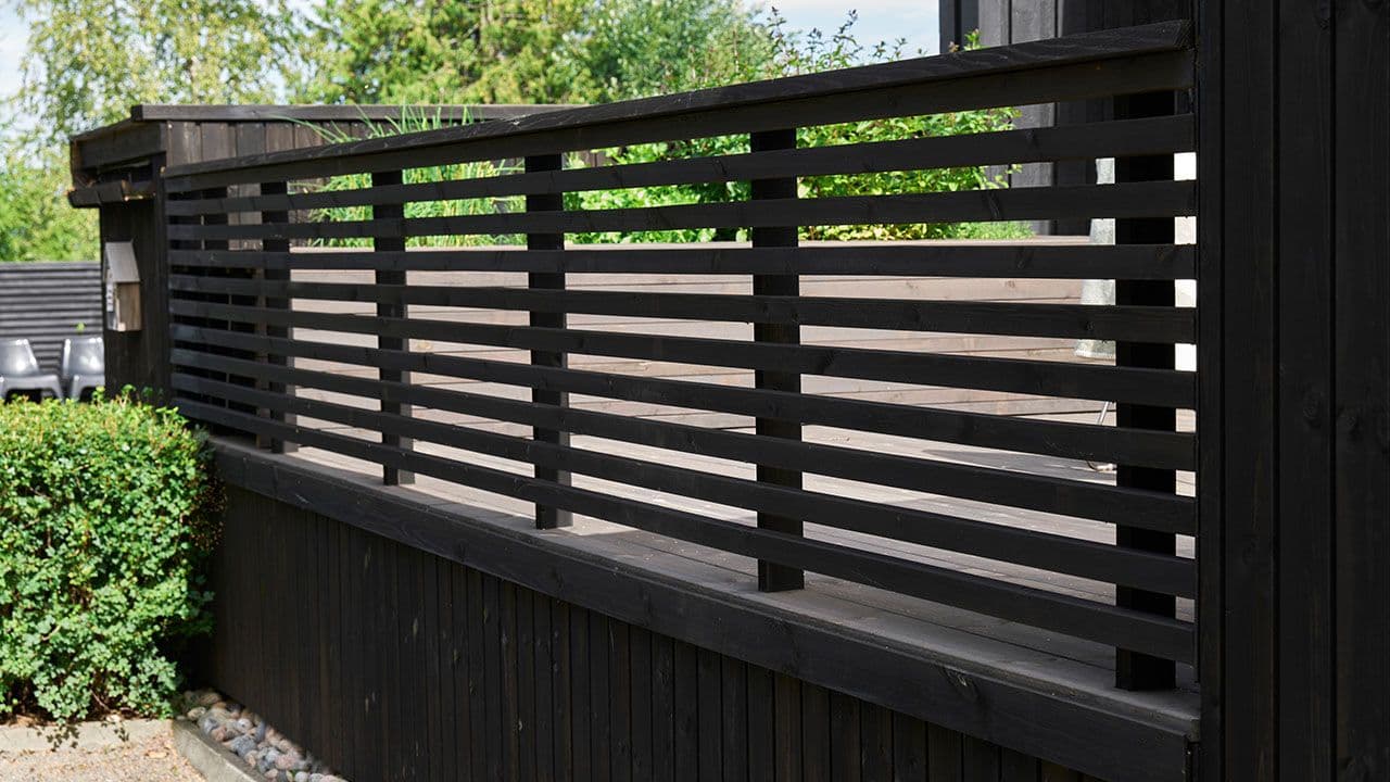 Terrasse med rekkverk av liggende lekter i sort.