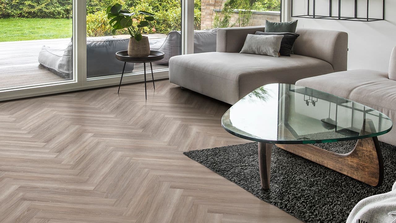 Brun fiskebensparkett i stue med moderne møbler og store vindusflater.