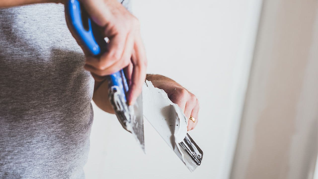 Person med to sparkelspader i hånden som skal helsparkle vegg.