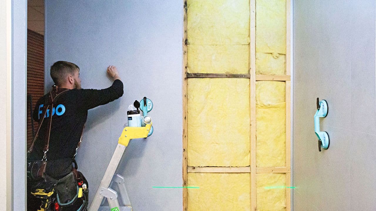 Håndverker som monterer baderomsplater i dusj.