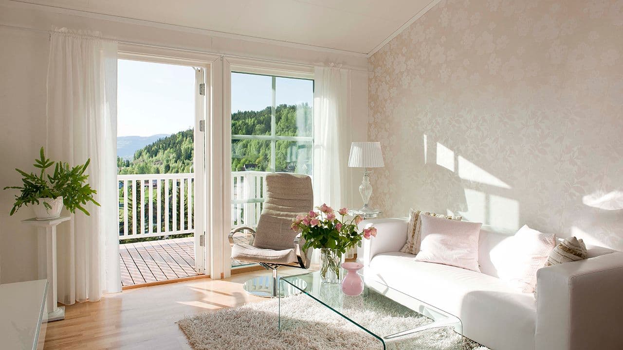 Stue med stort vindu i tre med sprosser og balkongdør.