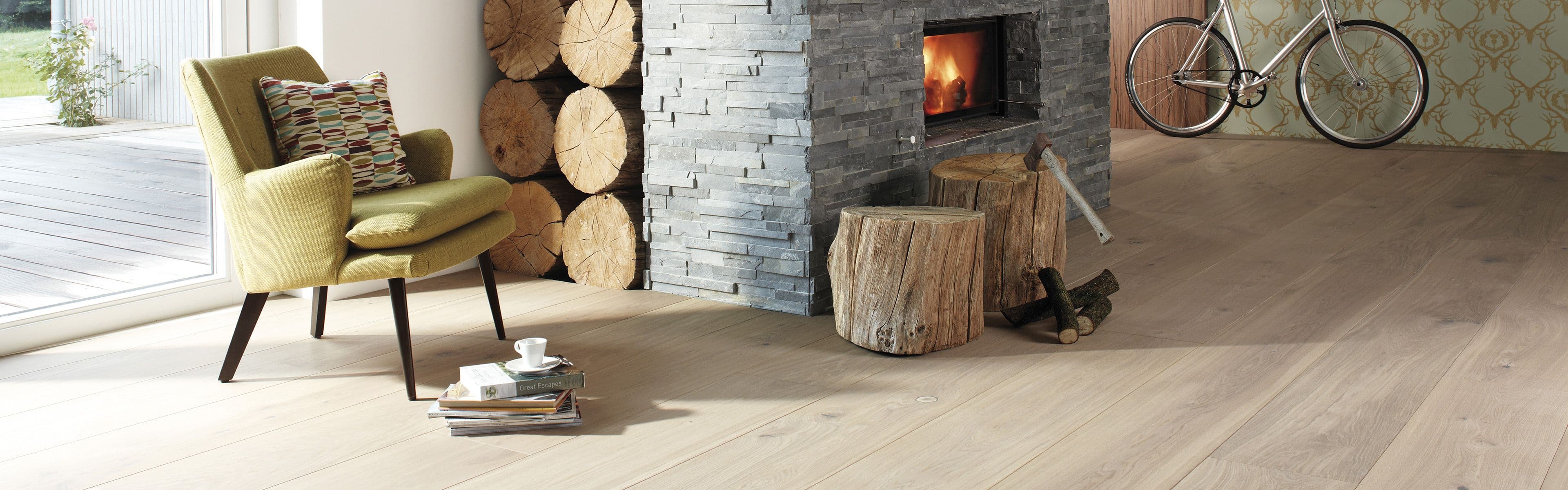 Parkettgulv i lys eik i stue med peis og lenestol med pute.