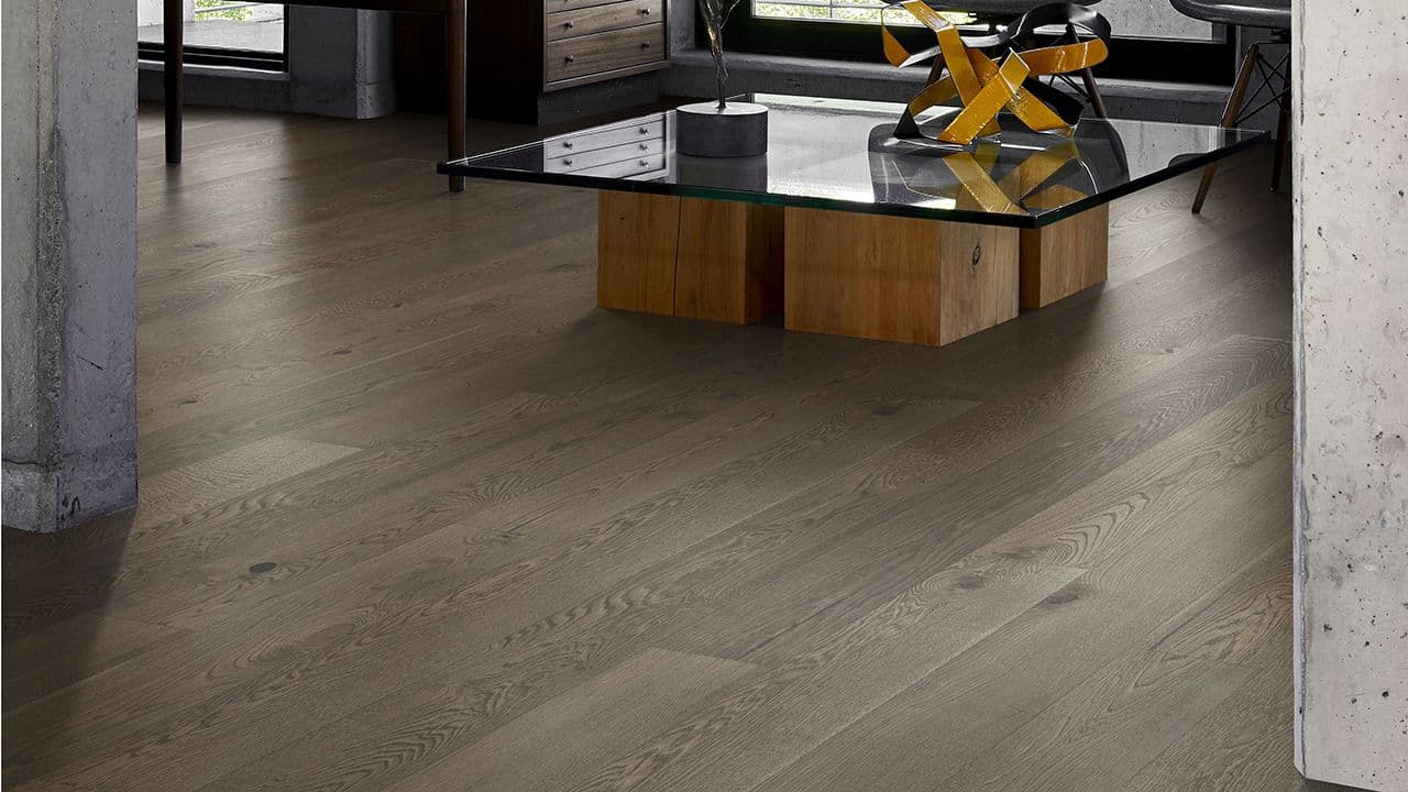 Mørk 1-stavs parkett i stue med glassbord.