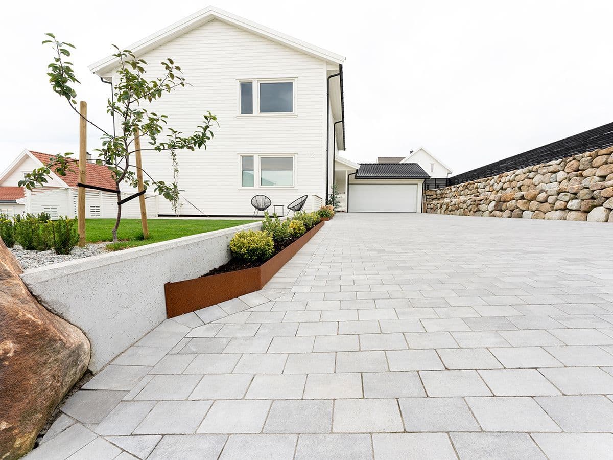 gårdsplass med rette linjer og belegningsstein. natursteinsmur langs den ene siden