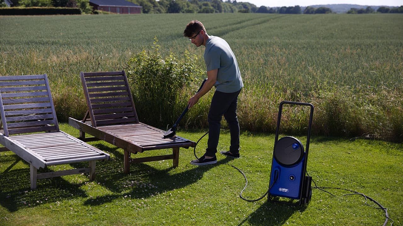 En som vasker hagemøbler med høytrykkspyler etter å ha byttet o-ringer.