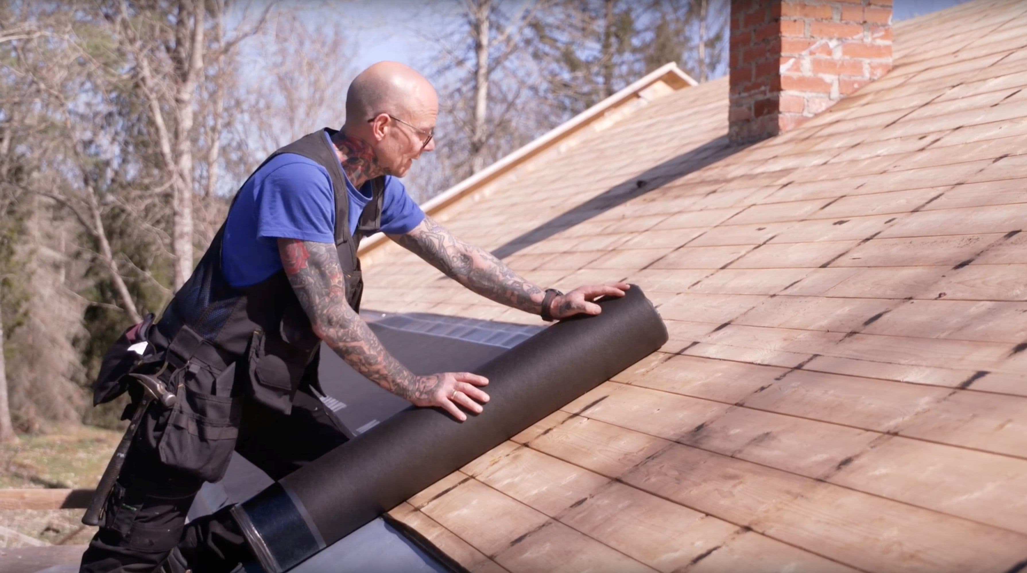 Mann som legger underlagsbelegg på tak.