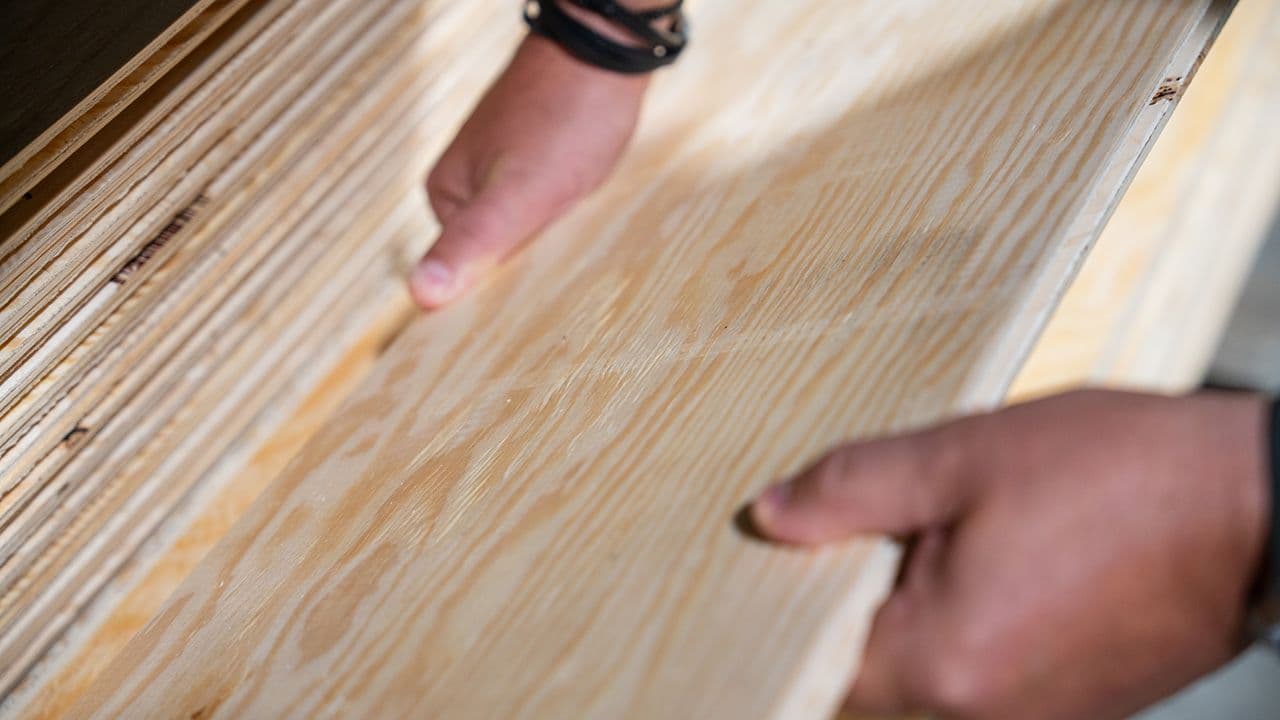 Hender som løfter kryssfiner.