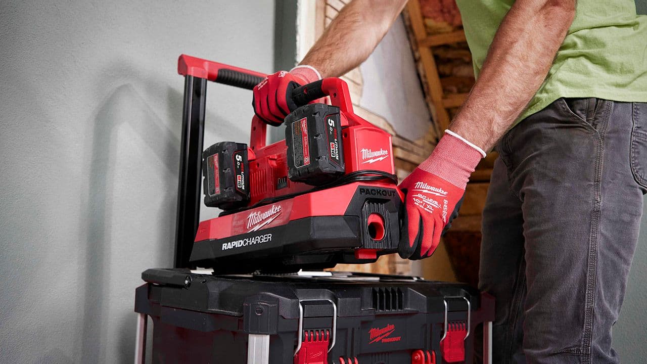 Håndverker som fester batteri-lader med batterier på verktøykasse.