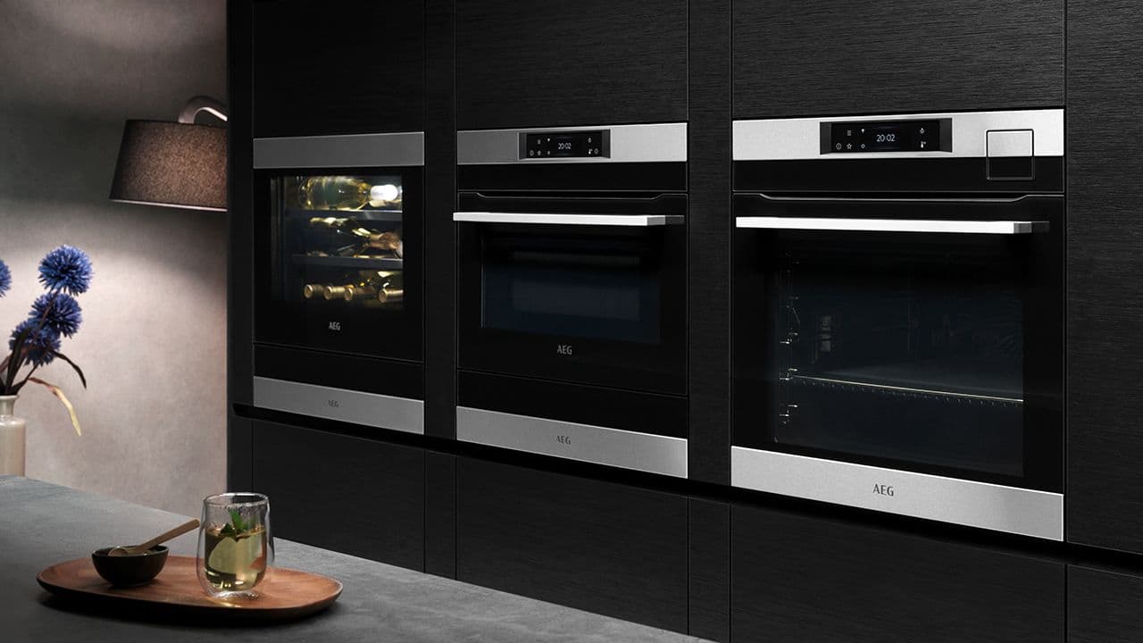 Svart kjøkken med høyskapsvegg med dampovn og kombiovn.