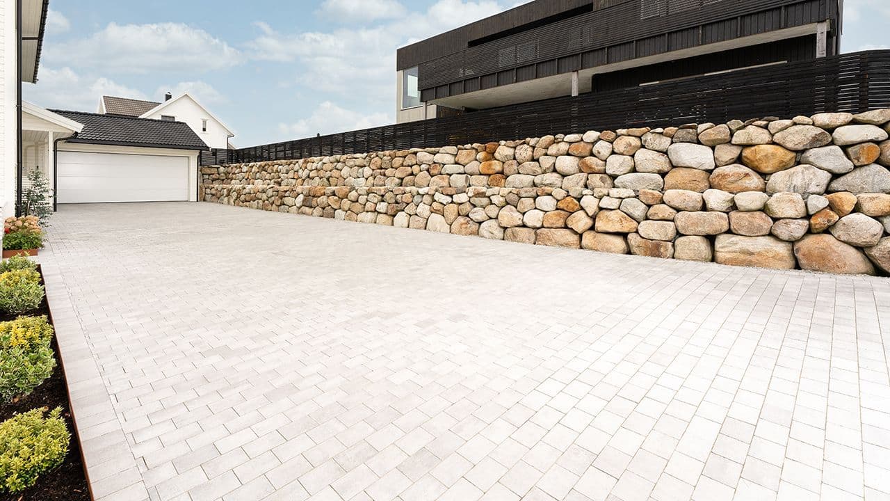 Multiblokk belegningsstein i oppkjørsel foran hvit garasje.