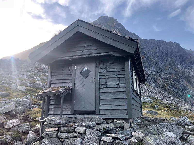 liten fjellstue med grå ytterdør og skifertak