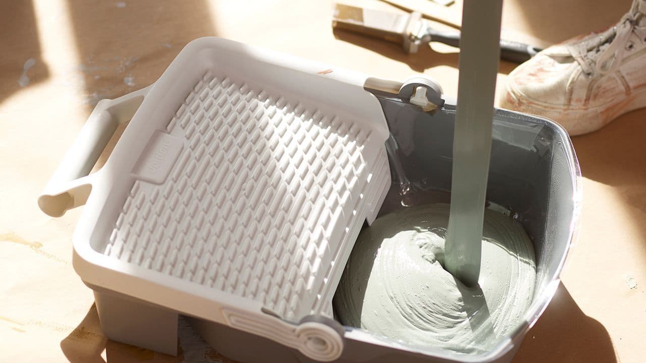 Lys grønn maling helles oppi et superbrett fra Jordan for å male gulv.