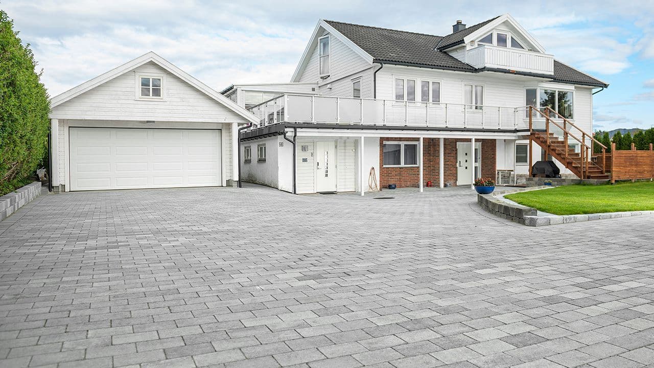Grå belegningsstein fra Multiblokk lagt foran hvitt hus og garasje.