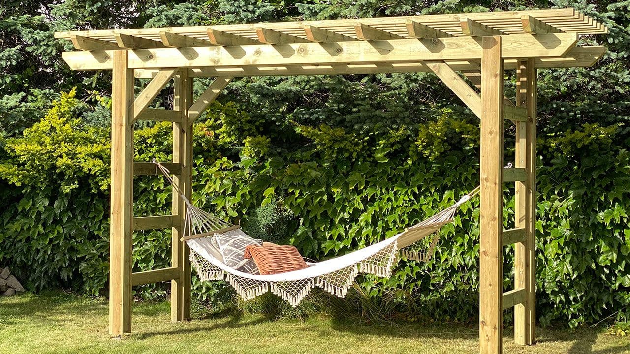 Grønn hage med liten frittstående pergola med hengekøye.