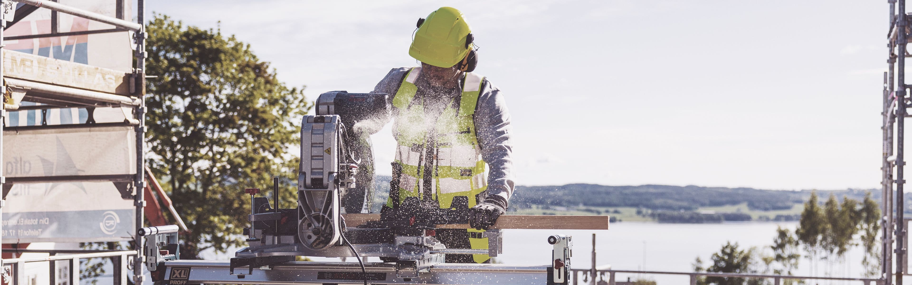 håndverker står på en byggeplass og sager materialer med sirkelsag