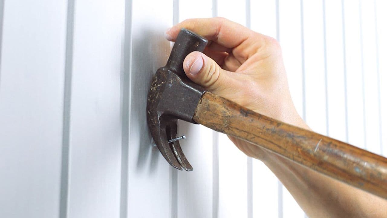 Hånd som fjerne spiker med hammer.