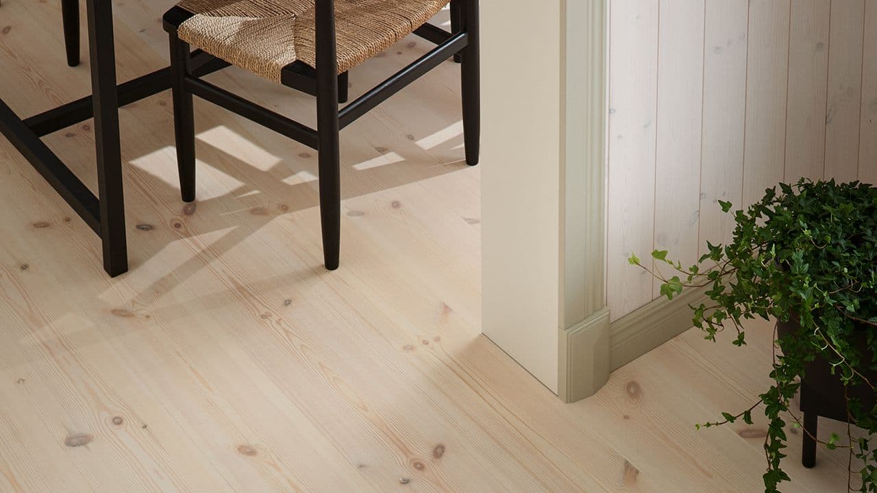 Furugulv i hytte med panelvegger og profilerte lister.