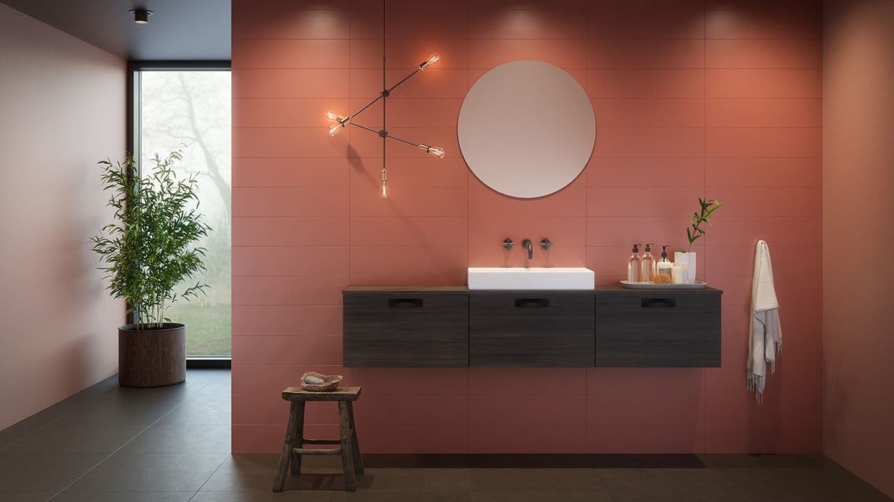 Bad i rød jordfarge med baderomsmøbel i mørkt treverk og rundt speil.