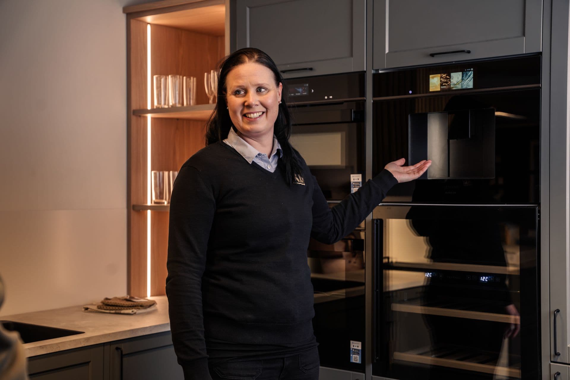 XL-BYGG-ansatt som viser frem hvitevarer i kjøkkenutstillingen.