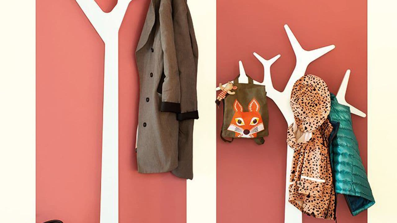 Entre malt i hvitt og korall med hvite klesstativ som ser ut som trær.