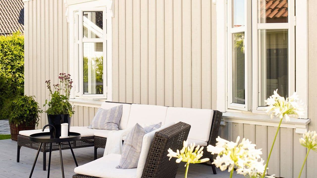 Lyst hus med ferdig malt utvendig kledning og beiset terrasse.