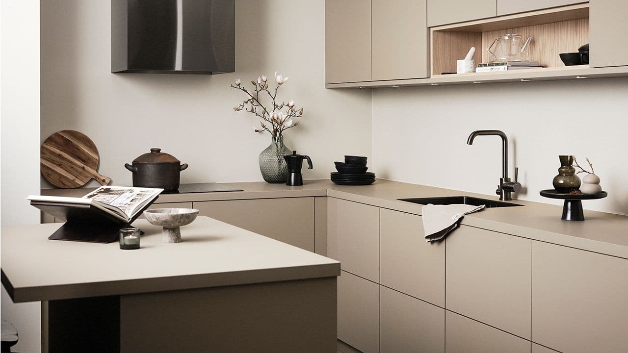 Liten kjøkkenøy i beige kjøkken med svart kjøkkenhette.